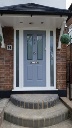 a blue front door sitting on the side of a brick building next to a set of steps