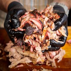 a person wearing black gloves is holding some meat