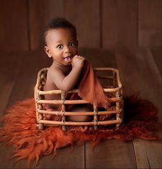 a baby is sitting in a basket on a wooden floor and posing for the camera