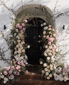 an entrance to a white building with flowers on it