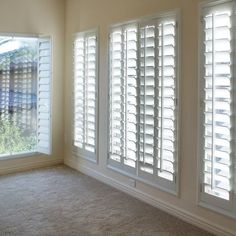 an empty room with white shutters and carpet