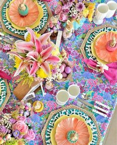 a colorful table setting with flowers, plates and utensils on the placemats