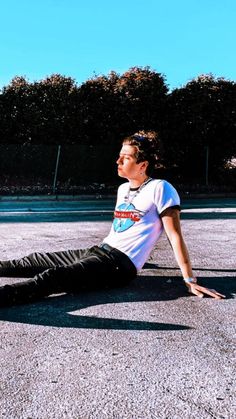 a young man laying on the ground with his feet up in the air while wearing black pants and a white t - shirt