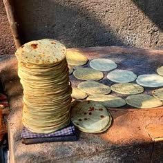 stack of tortillas sitting on top of a stone slab next to a pile of coins