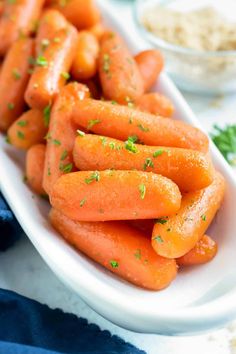 carrots in a white bowl with parsley on the top and other side dishes