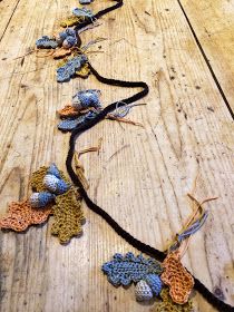 crocheted leaves and acorns are arranged on a wooden table with string