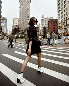 a woman walking across a street in high heels