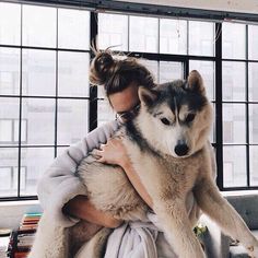 a woman holding a husky dog in her arms