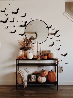 a table with pumpkins and bats on it in front of a wall mounted mirror