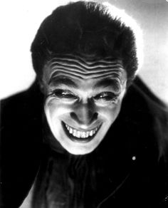 a black and white photo of a man with his face painted like a demon smiling