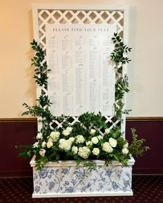 a table with flowers and greenery on it next to a sign that says please find your seat