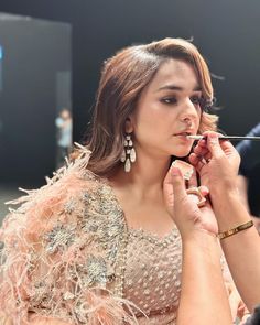 a woman is getting her make - up done by another woman in an evening dress