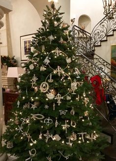 a christmas tree with ornaments on it in front of a stair case and staircase railing