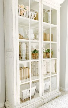 an old white china cabinet with glass doors