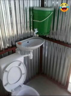 a white toilet sitting in a bathroom next to a green trash can on the wall