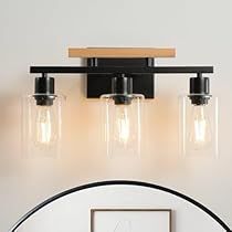 a bathroom vanity light with three lights and a mirror on the wall next to it