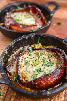 two cast iron pans filled with food on top of a wooden table