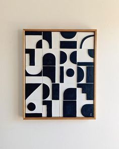 a black and white tile artwork hanging on the wall next to a wooden framed object