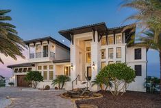 a large white house with palm trees in the front yard