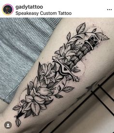 a black and white photo of a tattoo with flowers on the arm, done by an artist