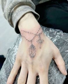 a person's hand with a rosary and cross tattoo on the middle of it