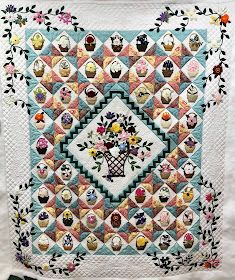 a quilted wall hanging with cupcakes and flowers in the center on it