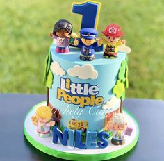 a birthday cake with the number one on it and toy figurines around it