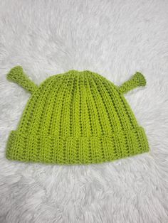 a green knitted hat laying on top of a white blanket