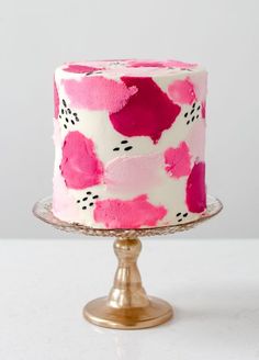 a pink and white cake sitting on top of a metal stand