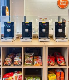 several machines are lined up on the counter in front of some snacks and coffee bags