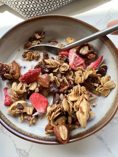 a bowl filled with granola and fruit on top of a table