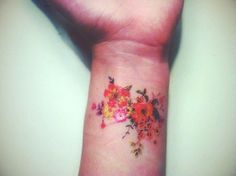 a woman's wrist tattoo with flowers on it