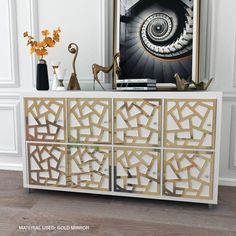 a white and gold sideboard with geometric designs on the front, in a living room