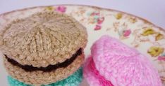 two small crocheted hats sitting on top of a white and pink plate next to each other