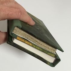 a hand holding an open book in front of a white background with only the pages visible