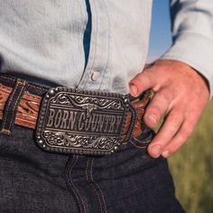 Wild, free, and born country. Show off your roots with this Born Country Attitude Buckle. Silver-toned "Born Country" runs across the center of the buckle with a longhorn steer sitting above. Classic filigree highlights the top and bottom and additional silver-toned borders add texture. Flowers, and silver-toned beads border the outer edge. The whole buckle is antiqued for dimension. Includes a standard 1.5 inch belt swivel. This is the perfect addition to complete your cowgirl wardrobe. This bu Western Concho Belt Buckles For Western-themed Events, Western Concho Belt Buckles For Country Events, Western Hand Tooled Belt Buckles For Rodeo, Engraved Western Belt Buckles For Western-themed Events, Engraved Western Belt Buckles For Rodeo, Adjustable Engraved Belt Buckles For Western-themed Events, Western Antique Belt Buckle For Rodeo, Western Adjustable Belt Buckles For Rodeo, Western Style Adjustable Belt Buckles For Rodeo