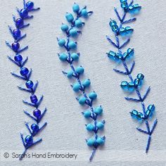 three different types of beaded flowers on a white table cloth with blue beads in the middle