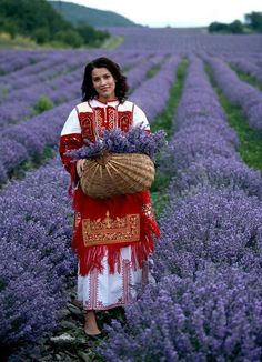 a woman standing in a lavender field holding a basket