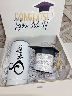 an open box containing a coffee mug and graduation cap with congratulations you did it written on the side