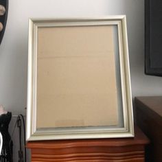 a white frame sitting on top of a wooden table next to a clock and other items