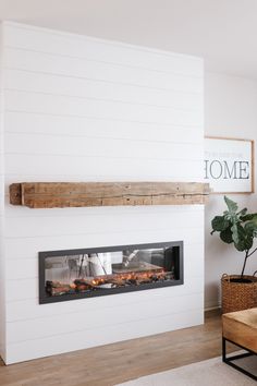 a living room with a fire place in the center and a potted plant next to it