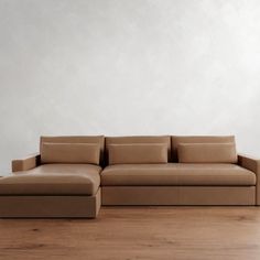 a couch sitting on top of a hard wood floor next to a white wall in an empty room