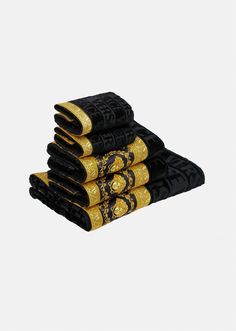 five black and gold napkins stacked on top of each other in front of a gray background