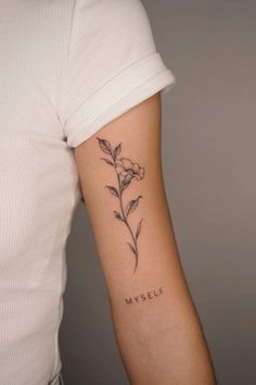 a woman's arm with a small flower tattoo on the left side of her arm