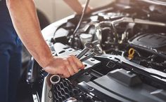 a man is working on the engine of a car with wrench and spanner