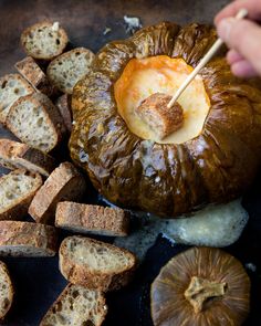 someone is dipping something into bread with a stick in the middle and other food on the side