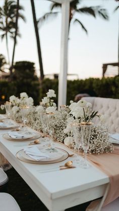 a long table with white flowers and place settings