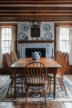 a dining room table and chairs with blue and white plates on the wall behind it