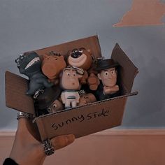 a person holding a cardboard box filled with small figurines