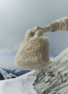 a woman holding onto a white bag on top of a snow covered mountain